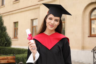 Mezuniyet gününde, bekar cüppeli ve diplomalı bir kız öğrenci.