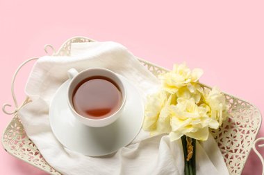 Çay tepsisi ve güzel narcissus çiçekleri renkli arka planda.