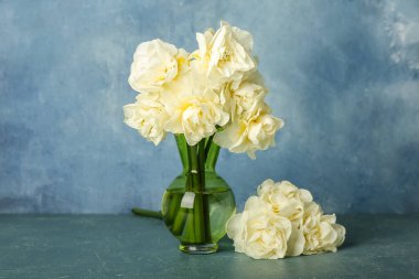 Renkli arkaplanda güzel narsisus çiçekleri olan vazo