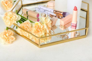 Narcissus çiçekleri, kozmetik ürünleri ve hafif arka planda aksesuarları olan bir tepsi.