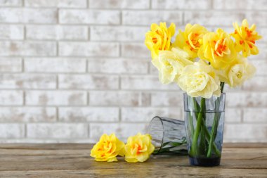 Tuğla duvarın yanında güzel narsist çiçekleri olan vazo
