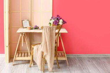 Renkli duvarın yanında sepetli ve leylak çiçekli modern işyeri