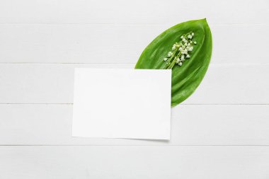 Güzel vadi zambağı çiçekleri ve açık ahşap arka planda boş bir kart.