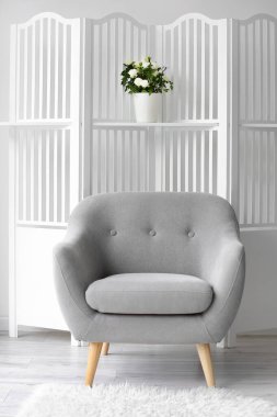 Koltuk ve katlanır ekran, ışık duvarına yakın çiçekler.