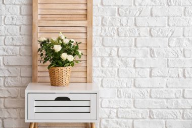 Tuğla duvarın yanındaki masada saksıda güzel beyaz güller