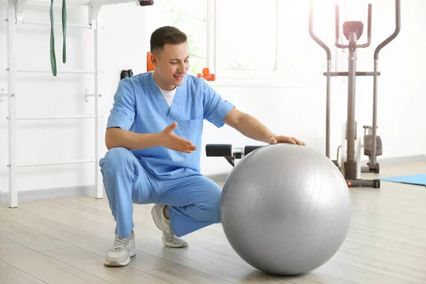 Male physiotherapist with fitball in rehabilitation center
