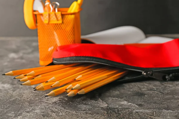 Pencil case with stationery on grunge background