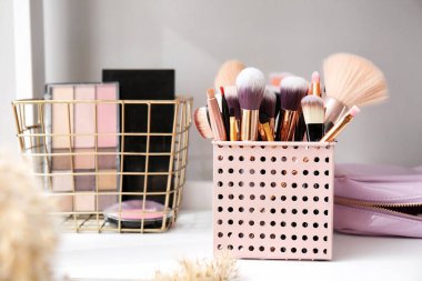 Makyaj fırçaları tutacakta ve kozmetik ürünleri masada, yakın plan.