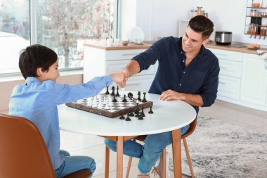 Father and son playing chess in kitchen
