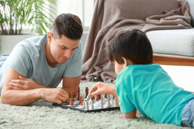 Baba ve oğul evde satranç oynuyor.