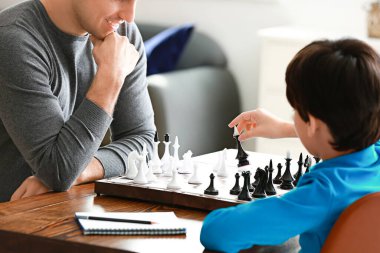 Baba ve oğul evde satranç oynuyor.