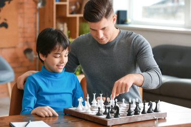 Baba ve oğul evde satranç oynuyor.