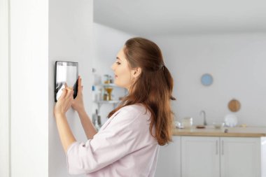 Akıllı ev güvenlik sistemi kontrol paneli kullanan kadın