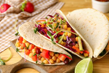 Hafif ahşap arka planda lezzetli vejetaryen tacoları olan bir pano. Yakın plan.