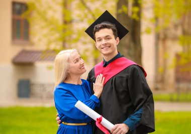 Mezuniyet gününde annesinin yanında mutlu bir genç adam.