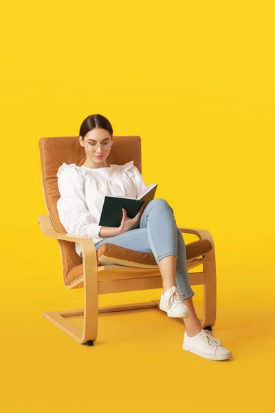 Young Woman Reading Book While Sitting Armchair Color Background — Stock Photo, Image