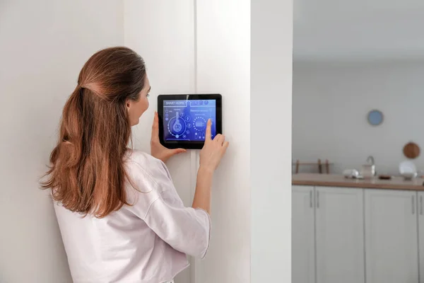 Woman using smart home security system control panel