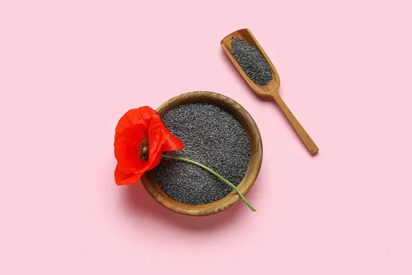 Bowl with poppy seeds and flower on color background