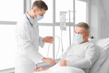 Doktor ve olgun adam klinikte kemoterapi görüyorlar.