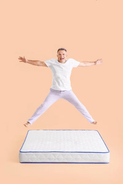 Glücklich Reifer Mann Springt Auf Matratze Vor Farbigem Hintergrund — Stockfoto