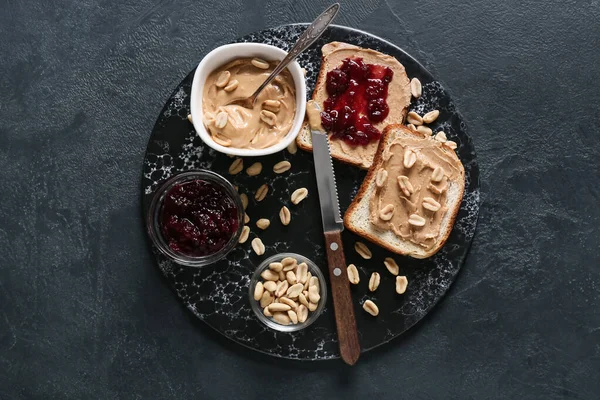 Bread with tasty peanut butter and jam on dark background