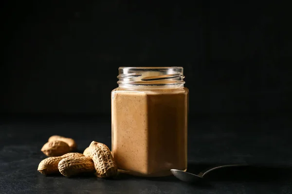 Glas Mit Leckerer Erdnussbutter Auf Dunklem Hintergrund — Stockfoto