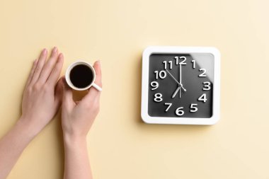 Bir fincan kahveli kadın elleri ve renkli arka planda şık bir saat.