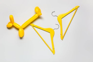 Balon köpeği ve elbiseler arka planda asılı.