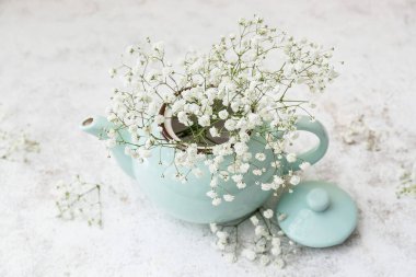 Aydınlık arka planda güzel çigila çiçekleri olan çaydanlık