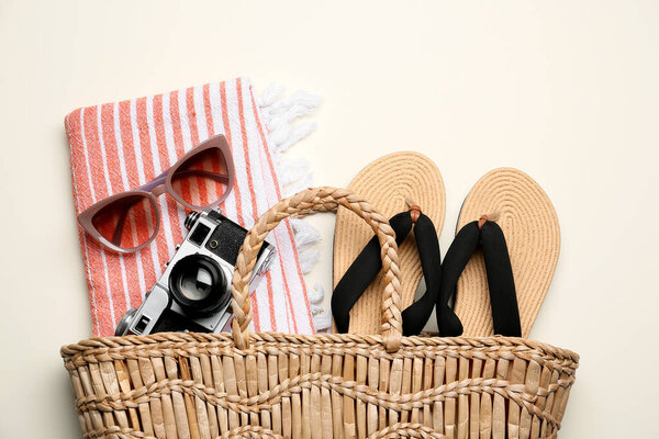 Bag with beach accessories and photo camera on color background