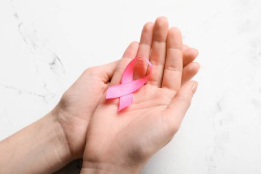 Arka planda pembe kurdeleli kadın eller, yakın plan. Göğüs kanseri farkındalığı konsepti