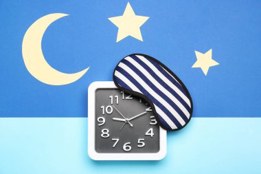 Renkli arka planda şık saat ve uyku maskesiyle kompozisyon