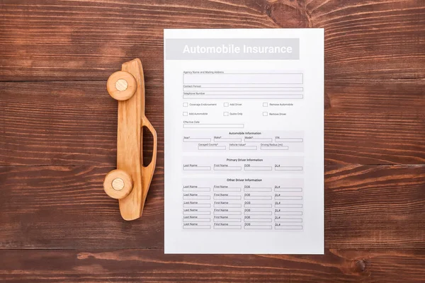 Automobile insurance and car figure on wooden background