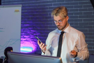 Geceleri ofisinde cep telefonu olan yakışıklı bir adam.