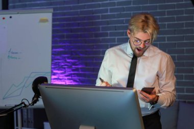 Geceleri ofisinde cep telefonu olan yakışıklı bir adam.