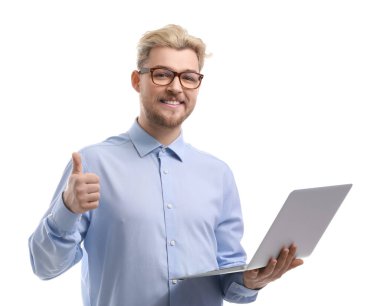 Bilgisayarlı mutlu genç adam beyaz arka planda baş parmağını gösteriyor.