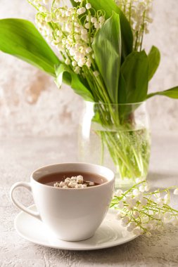 Vadideki güzel zambak çiçekleri ve arka planda bir fincan çay