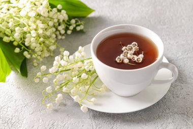 Vadideki güzel zambak çiçekleri ve arka planda bir fincan çay