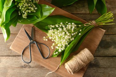 Vadideki güzel zambak çiçekleri, ahşap arka planda ip ve makas.