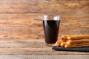 Lezzetli churros ve ahşap arka planda bir bardak kola.