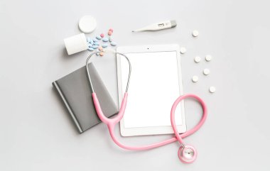 Steteskoplu tablet bilgisayar ve gri arka planda haplar