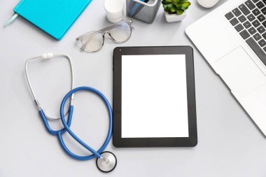 Steteskoplu tablet bilgisayar ve gri arkaplanda dizüstü bilgisayar