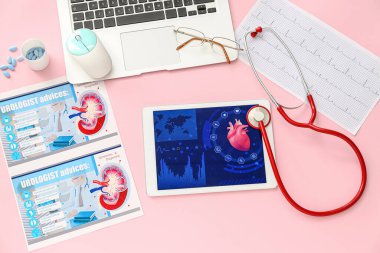 Renk arkaplanında steteskop, kardiyogram ve ürolog aksesuarları olan tablet bilgisayar