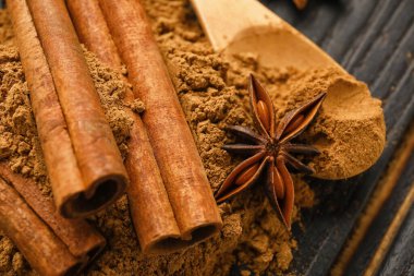 Tarçın çubukları ve tahta arka planda pudra, yakın plan.