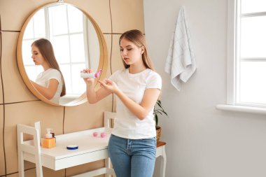 Genç kız evde sivilceler için tedavi uyguluyor.