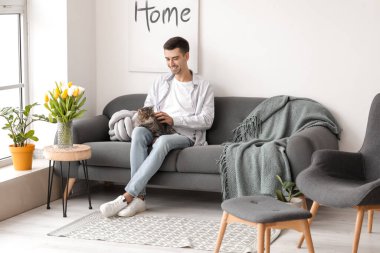 Oturma odasında kedisi olan genç bir adam.