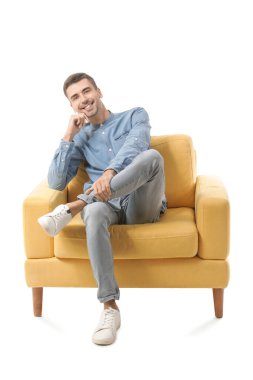 Genç adam beyaz arka planda koltukta oturuyor.