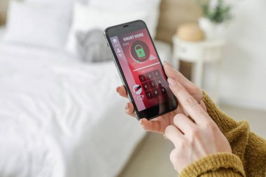 Akıllı ev güvenlik sistemi uygulaması kullanan cep telefonu olan kadın, kapat
