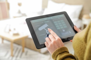 Akıllı ev güvenlik kontrol paneli kullanan kadın, yakın plan.