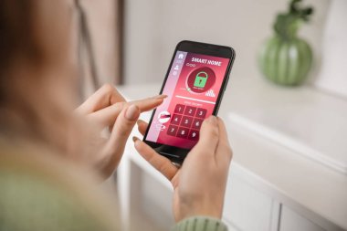 Akıllı ev güvenlik sistemi uygulaması kullanan cep telefonu olan kadın, kapat